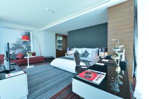 マナーマにあるRamee Grand Hotel And Spaのベッド、デスク、テレビが備わるホテルルームです。