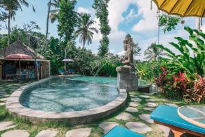 a pool at a resort with a statue in the middle at Bersila La Maison Du Bonheur in Payangan