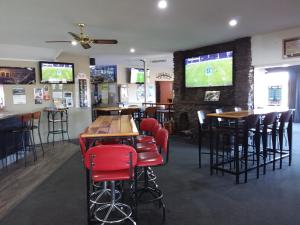 bar z czerwonymi krzesłami, stołami i telewizorami w obiekcie Pine Lake View Lodge w mieście Kaiapoi
