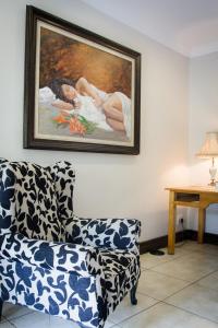 a living room with a couch and a painting on the wall at De Zoete Rust Guesthouse in Centurion