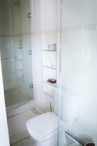a white bathroom with a toilet and a shower at De Zoete Rust Guesthouse in Centurion