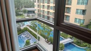 een raam met uitzicht op een zwembad bij rain condo 2 bedroom by leelawadee in Cha Am