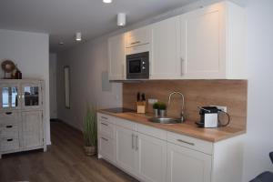 a kitchen with white cabinets and a sink at Apart Seegras in Büsum