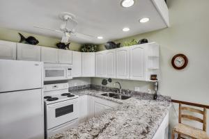 a white kitchen with white cabinets and a sink at Pupukea Condo in Kahuku