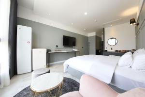 a bedroom with a white bed and a tv at Hotel Raum Suncheon in Suncheon