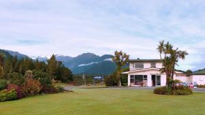 a house with palm trees and mountains in the background at Glacier View Motel - Franz Josef in Franz Josef