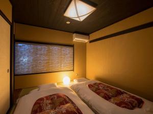 1 dormitorio con 2 camas, ventana y luz en Rinn Manjuji, en Kioto