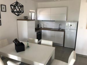 una cucina con armadi bianchi e tavolo con sedie di Villa Lorenta Apartments a Primošten