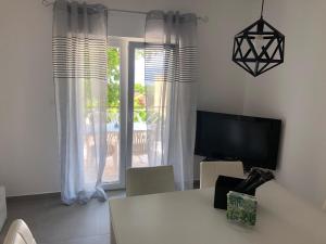 sala de estar con mesa, TV y ventana en Villa Lorenta Apartments, en Primošten
