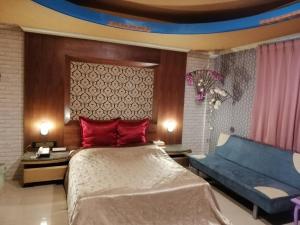 a bedroom with a large bed and a blue couch at Sydney Motel in Tucheng