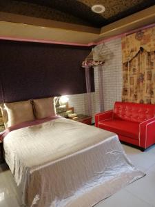a bedroom with a bed and a red couch at Sydney Motel in Tucheng