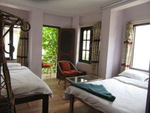 una camera con due letti e una sedia e finestre di STUPA VIEW INN a Kathmandu