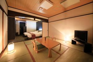 a living room with a room with a bed and a table at Hotel Kamogawaso in Takekara