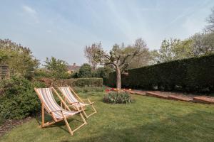 2 chaises assises dans l'herbe du jardin dans l'établissement Henley self catering House, à Henley-on-Thames