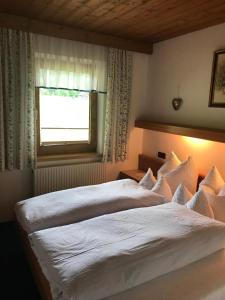 a bedroom with a large white bed with a window at Ferienwohnungen Schleich in Nassereith