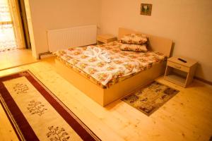 a small bedroom with a bed and a rug at Pensiunea La Cernat in Şugag