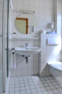 a white bathroom with a sink and a mirror at Hotel Tannenhof in Steinen