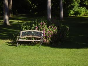 um banco de parque sentado na relva ao lado de flores em La Grange des Marettes em Cléres