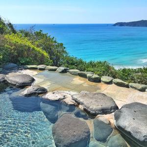 a swimming pool with rocks and the ocean in the background at Shimoda Yamatokan in Shimoda