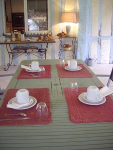 une table avec des assiettes et des tasses en haut dans l'établissement La Grange des Marettes, à Cléres