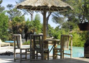 una mesa y sillas bajo una sombrilla junto a una piscina en Bambou House, en Aix-en-Provence