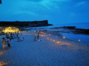 un gruppo di persone su una spiaggia di notte di Hotel Hieracon a Carloforte