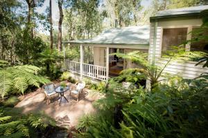 ein Haus mit einem Tisch und Stühlen in einem Garten in der Unterkunft Myers Creek Cascades Luxury Cottages in Healesville