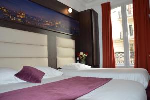 two beds in a hotel room with a large window at Parc Hotel in Paris