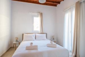 una camera da letto con un letto bianco con due asciugamani di The Corfos Hills House a Ornos