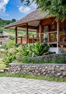 a house with a stone wall in front of it at Kokomo Resort Gili Gede in Gili Gede