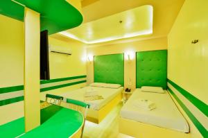 two beds in a room with green and yellow walls at Hotel 99 Monumento in Manila