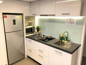 a kitchen with a white refrigerator and a sink at KL Sentral Bangsar Suites EST BY PSM LUXURY SUITES in Kuala Lumpur