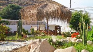 - un jardin avec une table et une cabane en paille dans l'établissement Liogerma, à Adamas