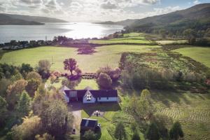 an aerial view of a house in a field next to a lake at Powdermills B & B in Inveraray