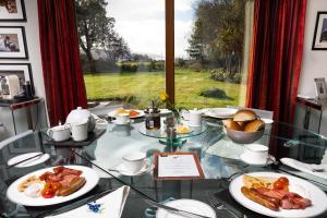 uma mesa de vidro com pratos de comida e uma janela em Powdermills B & B em Inveraray