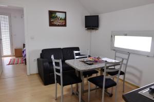 a dining room with a table and chairs and a screen at DELUXE Apartmani Lola - Vrnjačka banja in Vrnjačka Banja