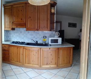 a kitchen with wooden cabinets and a microwave at Trilocale BELVEDERE Alloggio ad uso turistico - VDA - LA THUILE - CIR 0068 in La Thuile +23 photos
