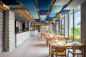 un restaurant avec des tables et des chaises en bois ainsi que des fenêtres dans l'établissement Cross Pattaya Oceanphere - formerly X2 Pattaya Oceanphere, à Bang Sare