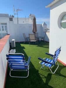 two blue chairs sitting on a patio with grass at Atico Cielos 102 in El Puerto de Santa María