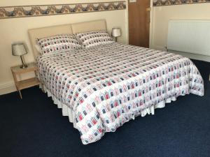 a bedroom with a large bed with a checkered blanket at The Kathrene Holiday Flats in Fleetwood