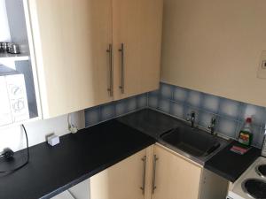 a kitchen with a sink and a black counter top at The Kathrene Holiday Flats in Fleetwood