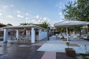 a patio with white umbrellas and tables and chairs at Amour Holiday Resort in Sidari