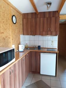 a kitchen with wooden cabinets and a clock on the wall at Noclegi na Zaciszu in Kąty Rybackie