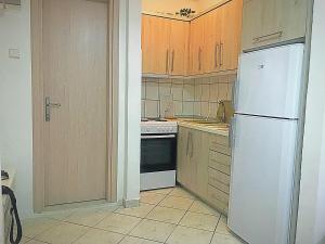 a kitchen with a white refrigerator and wooden cabinets at Alex Flat in Neoi Epivates