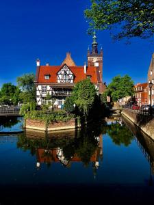 a building with a clock tower next to a river at Apartament Teatralny in Gdańsk