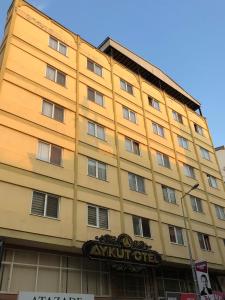 ein gelbes Gebäude mit einem Schild davor in der Unterkunft Aykut Palace Otel in İskenderun