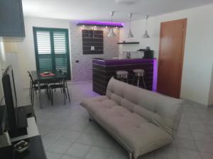 a living room with a couch and a kitchen with purple lighting at Marlen's House in Bernalda
