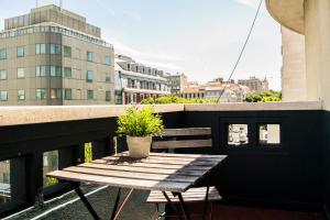 Avenue Hostel & Suites في لشبونة: طاولة خشبية على شرفة مع نبات الفخار