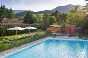 einen Pool mit Stühlen und Sonnenschirmen neben einem Haus in der Unterkunft Hotel Iris in Pescasseroli