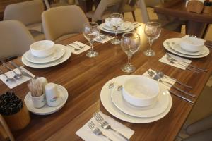 a wooden table with white plates and wine glasses at Cmr Aydogan Hotel in Rize